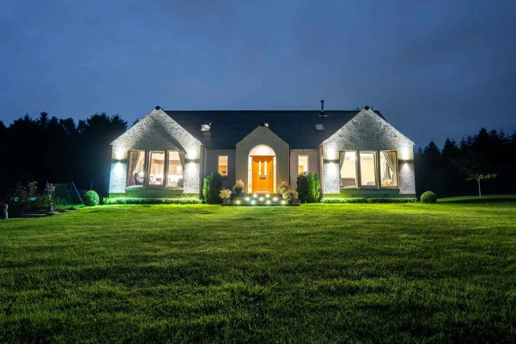 a house with a green lawn at night at Drumlochy B&B in Inverness