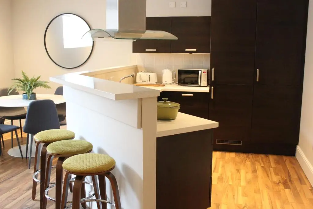 a kitchen with black and white cabinets and stools at The Bell Tower in Inverness