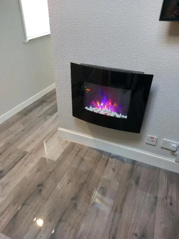 a living room with a fireplace in a wall at The Treehouse by Airlie in Nairn