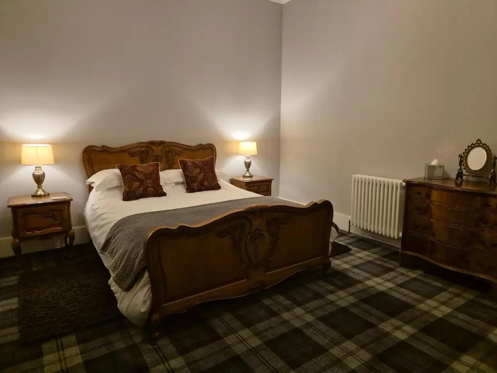 a bedroom with a large bed and two night stands at The Old Convent Holiday Apartments in Fort Augustus