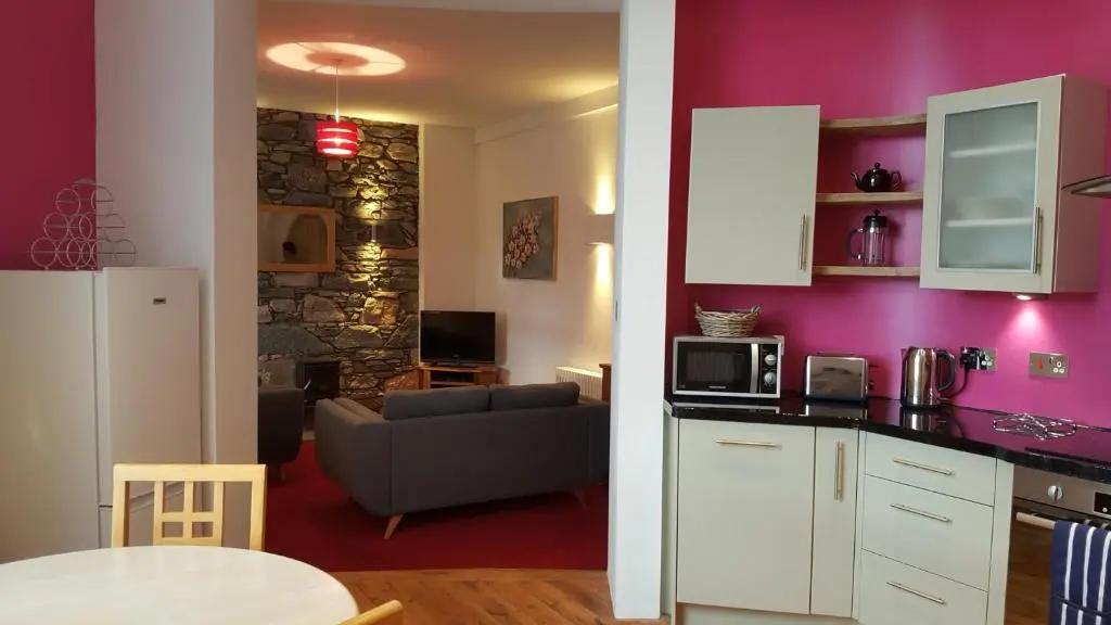 a kitchen and a living room with purple walls at The Old Convent Holiday Apartments in Fort Augustus