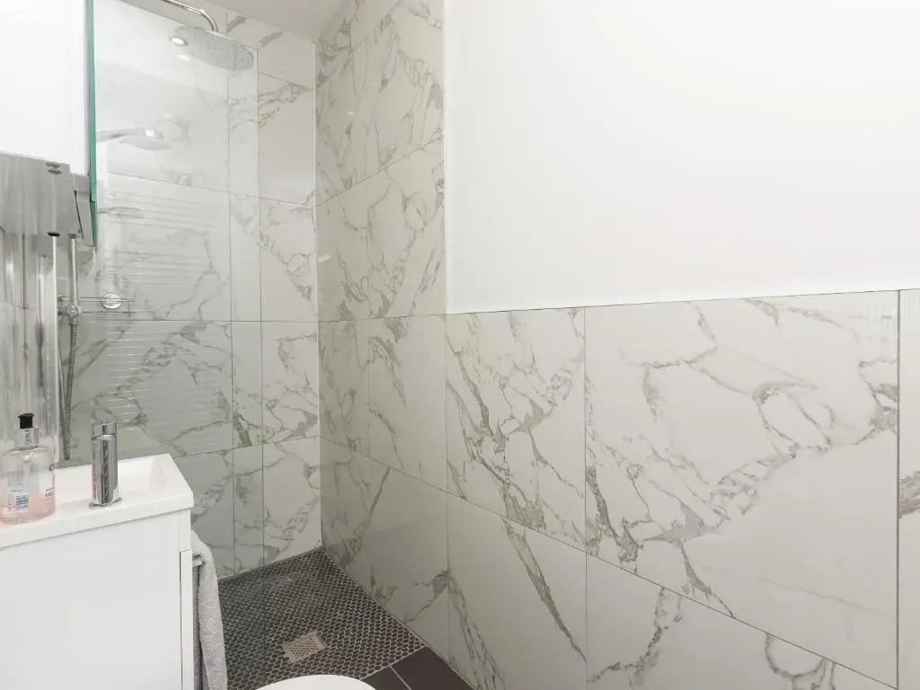 a bathroom with marble walls and a shower with a toilet at Inverspey in Kingston