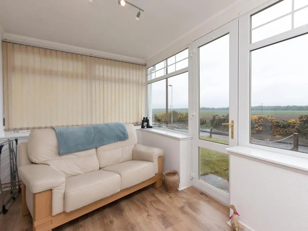 a living room with a white chair and large windows at Inverspey in Kingston