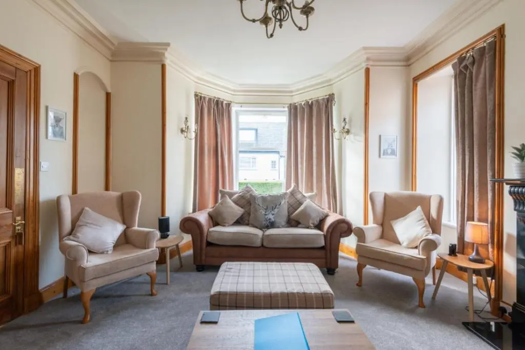 a living room with a couch and two chairs at Aye Stay Home, city centre in Inverness