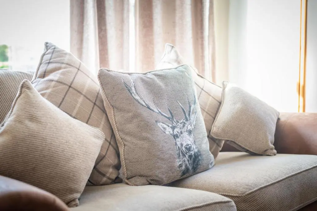 a pile of pillows on a couch with a window at Aye Stay Home, city centre in Inverness