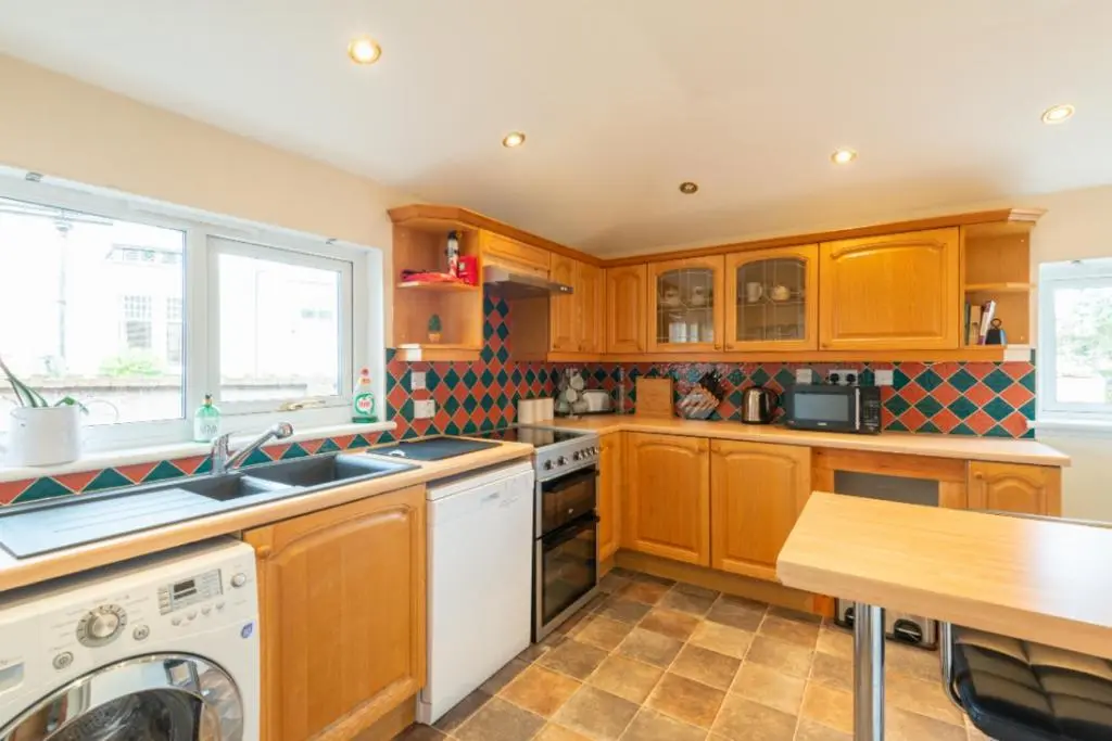 a kitchen with wooden cabinets and a white dishwasher at Aye Stay Home, city centre in Inverness