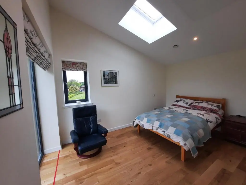 a bedroom with a bed and a chair and a window at Carnmore Cottage in Inverness