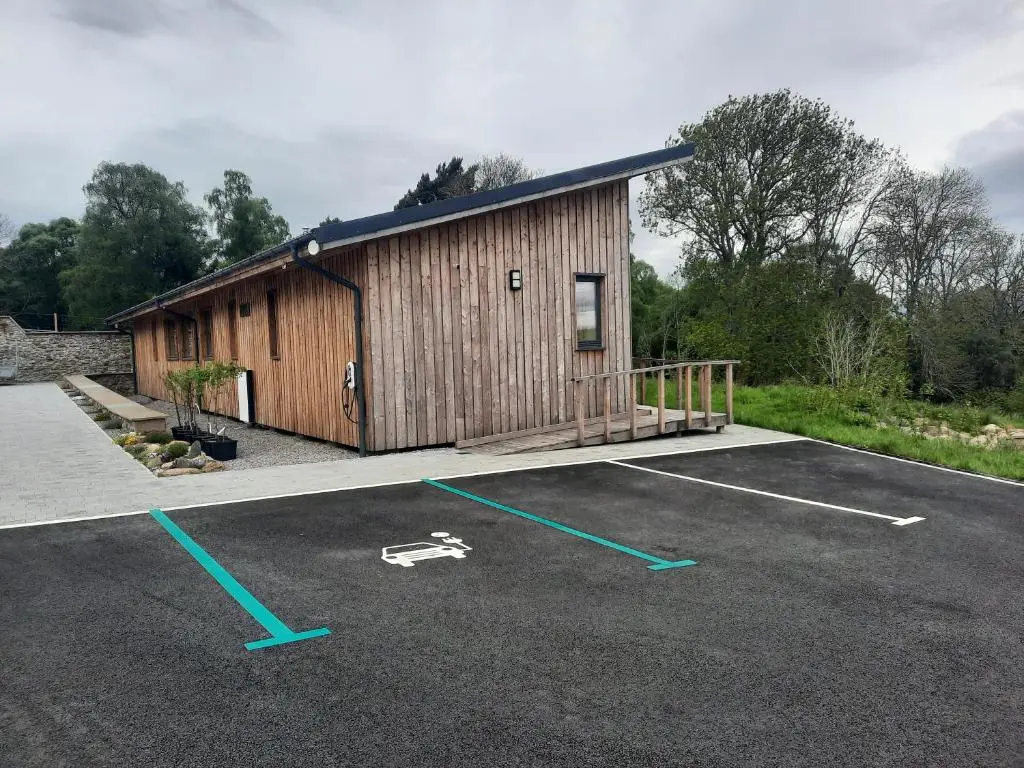 a building with a parking lot in front of it at Carnmore Cottage in Inverness