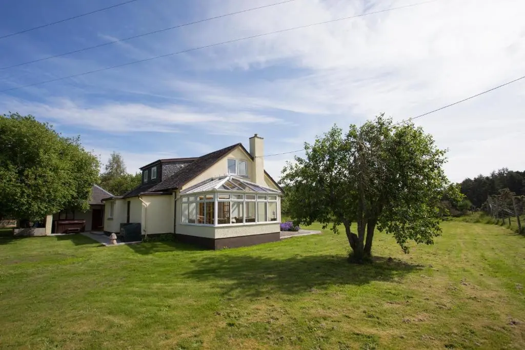 a house with a tree in the yard at Juniper Hill Loch Achilty in Contin