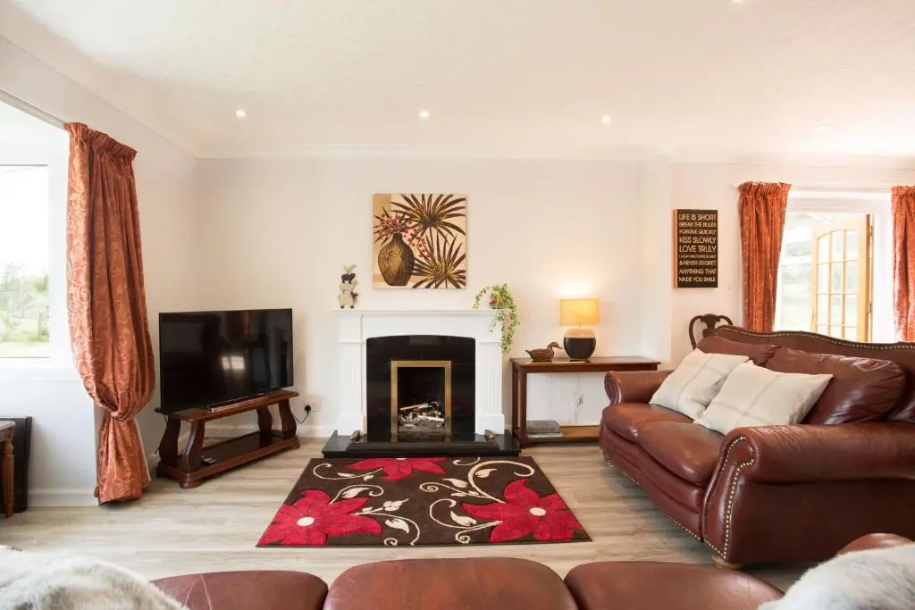 a living room with a couch and a fireplace at Juniper Hill Loch Achilty in Contin