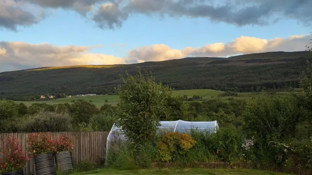 a garden with a fence and mountains in the background at The Studio in Drumnadrochit