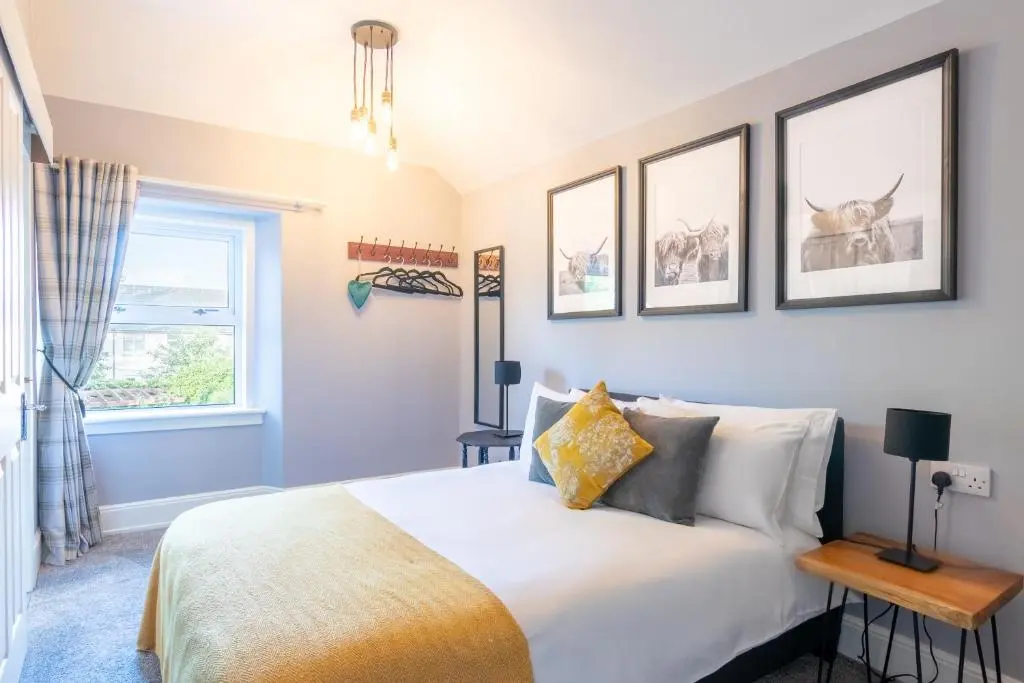 a bedroom with a bed and three pictures on the wall at West of the Ness in Inverness