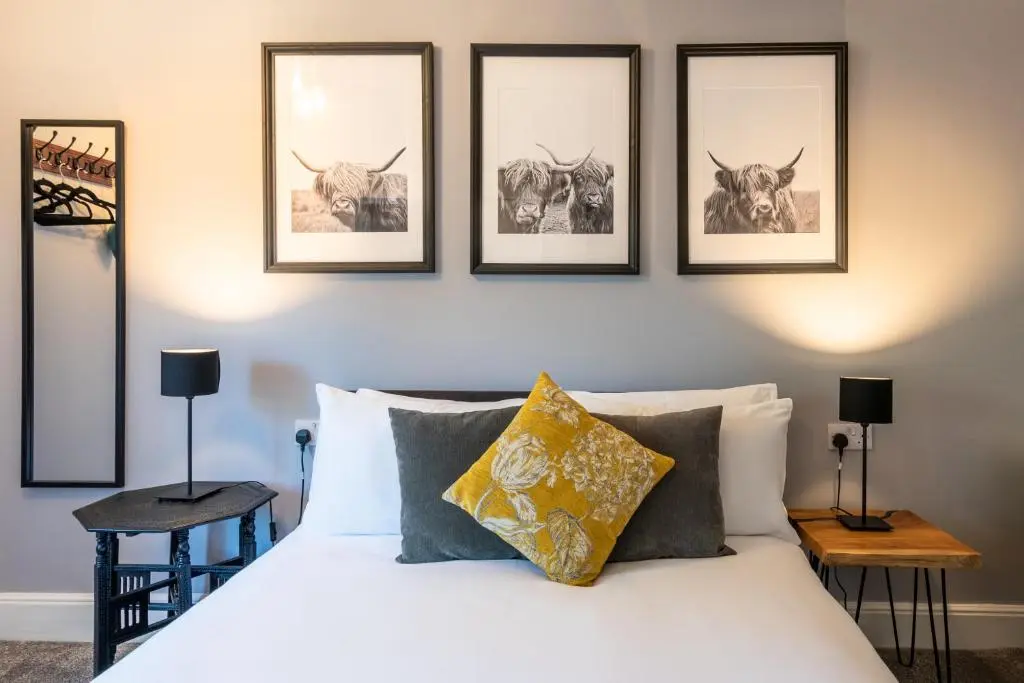a bedroom with a bed with four pictures on the wall at West of the Ness in Inverness