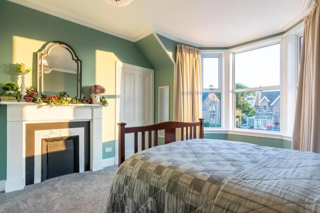 a bedroom with a bed and a fireplace and a mirror at West of the Ness in Inverness