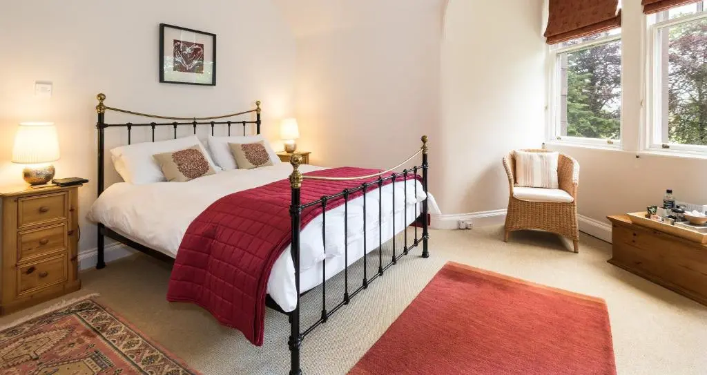 a bedroom with a bed with a red blanket at Coig na Shee Guest House in Newtonmore