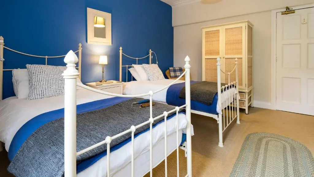 two beds in a bedroom with blue walls at Coig na Shee Guest House in Newtonmore
