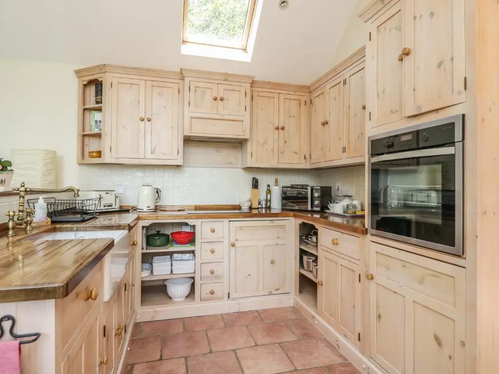 a large kitchen with wooden cabinets and a window at Drumhead Bothy in Banchory