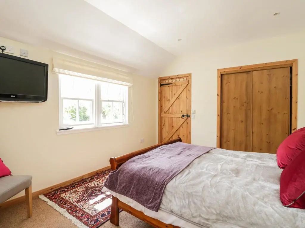 a bedroom with a bed and a tv on the wall at Drumhead Bothy in Banchory