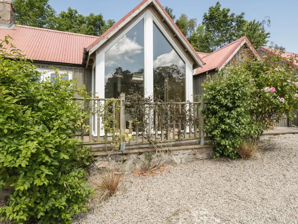 a house with a fence and some bushes at Drumhead Bothy in Banchory