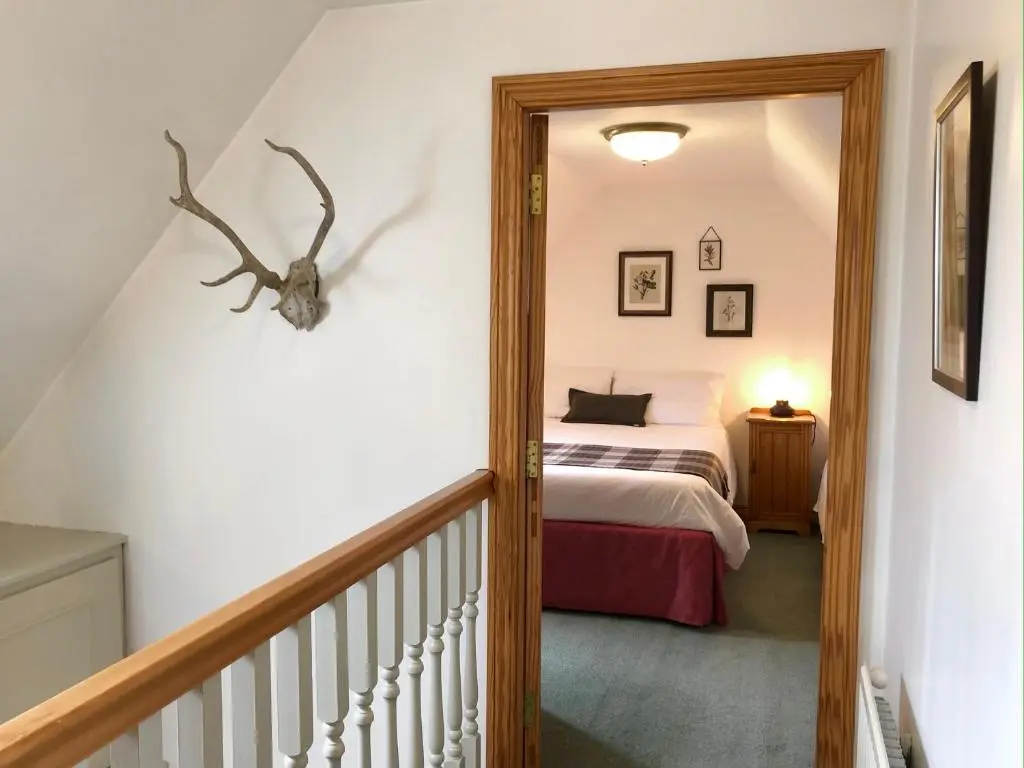a bedroom with a bed and a staircase with a mirror at Glenmuir Cottage in Dornoch