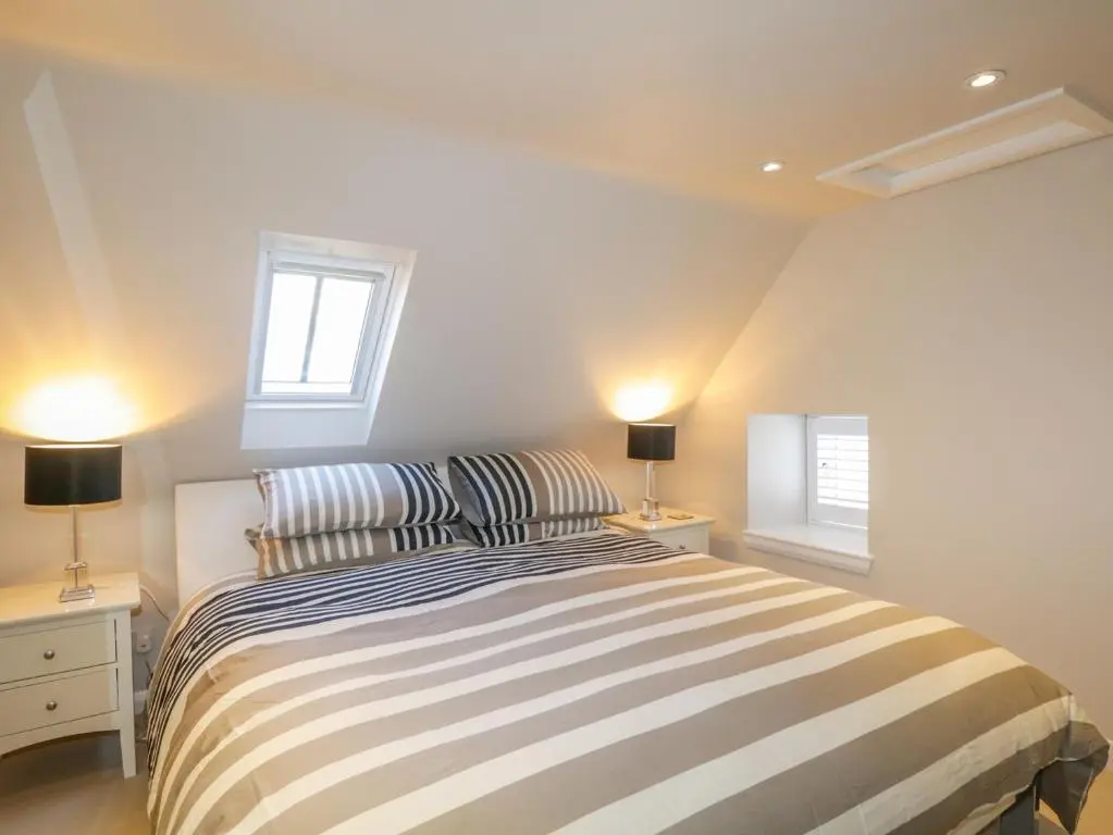 a bedroom with a striped bed and two lamps at 36 Sandend Village in Banff