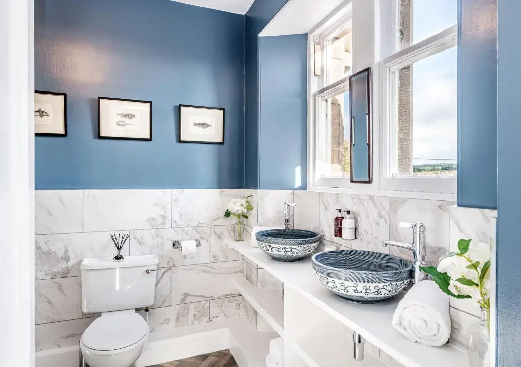 a bathroom with blue walls and a toilet and two sinks at The Old Manse, Loch Ness (highland-escape) in Inverness