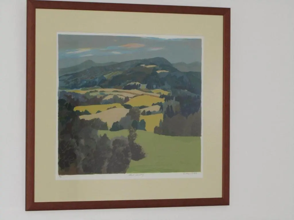 a framed painting of a valley with hills and trees at River Walk Inverness in Inverness