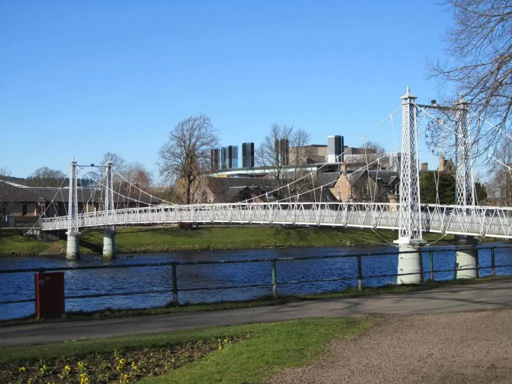 a white bridge over a river in a city at River Walk Inverness in Inverness