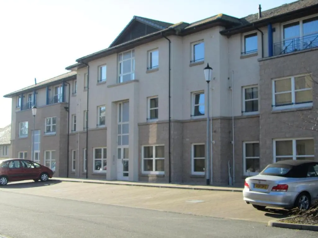a large brick building with cars parked in a parking lot at River Walk Inverness in Inverness