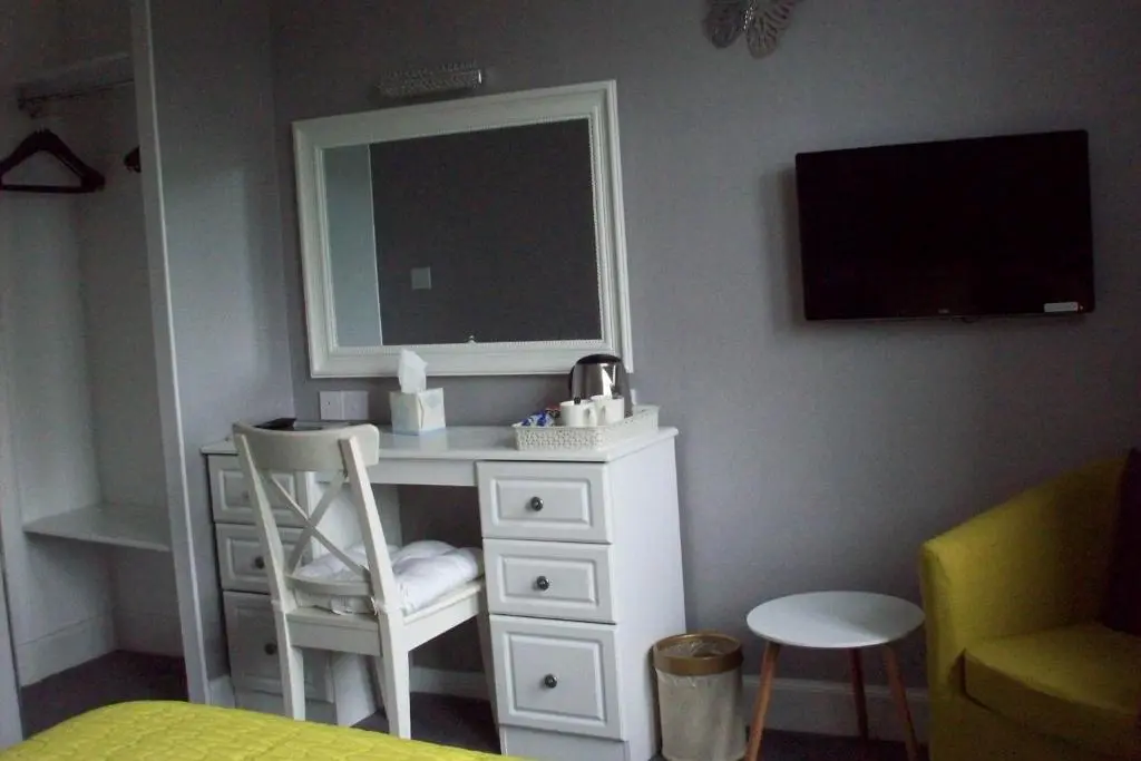 a bedroom with a desk with a mirror and a chair at Lairg Highland Hotel in Lairg