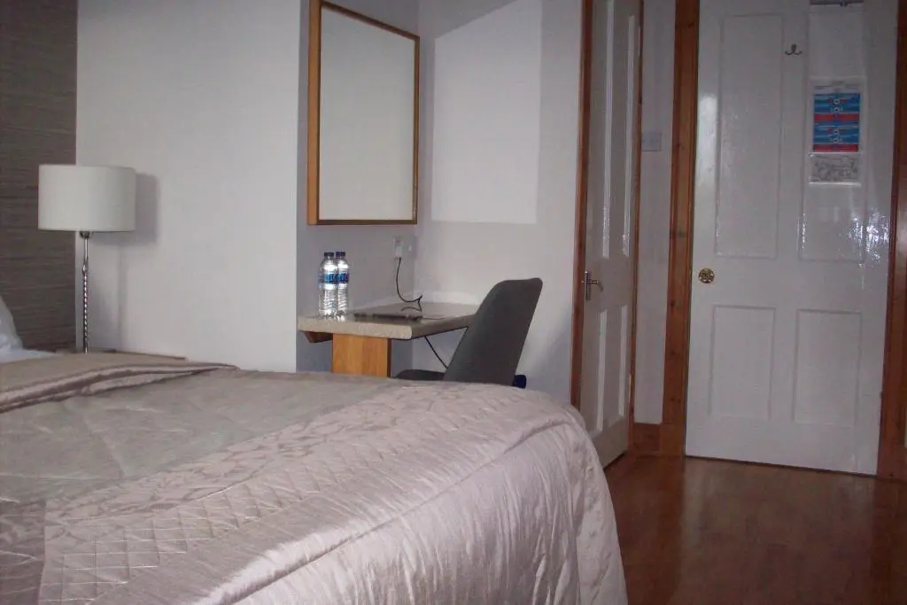 a bedroom with a bed and a desk with a chair at Lairg Highland Hotel in Lairg