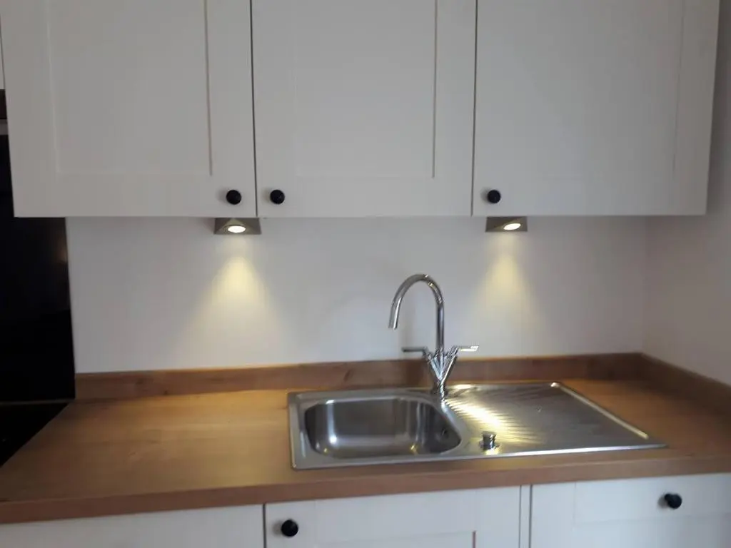 a kitchen counter with a sink and white cabinets at The Cabin at No 45 in Ballater