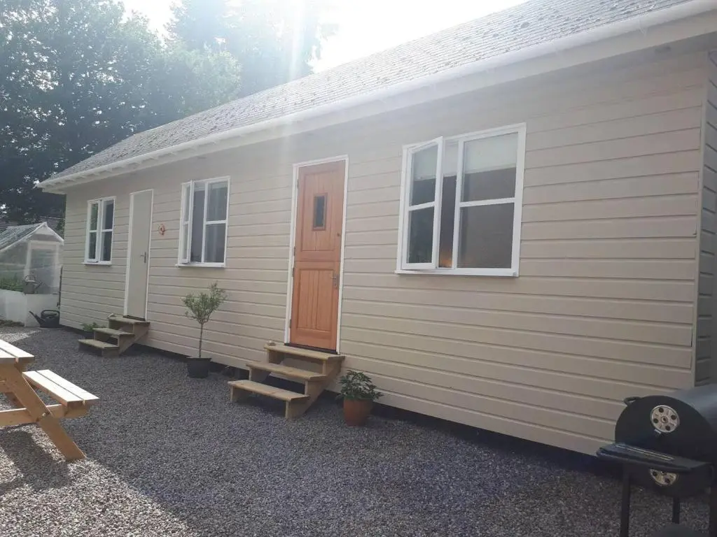 a small white building with a door and benches at The Cabin at No 45 in Ballater