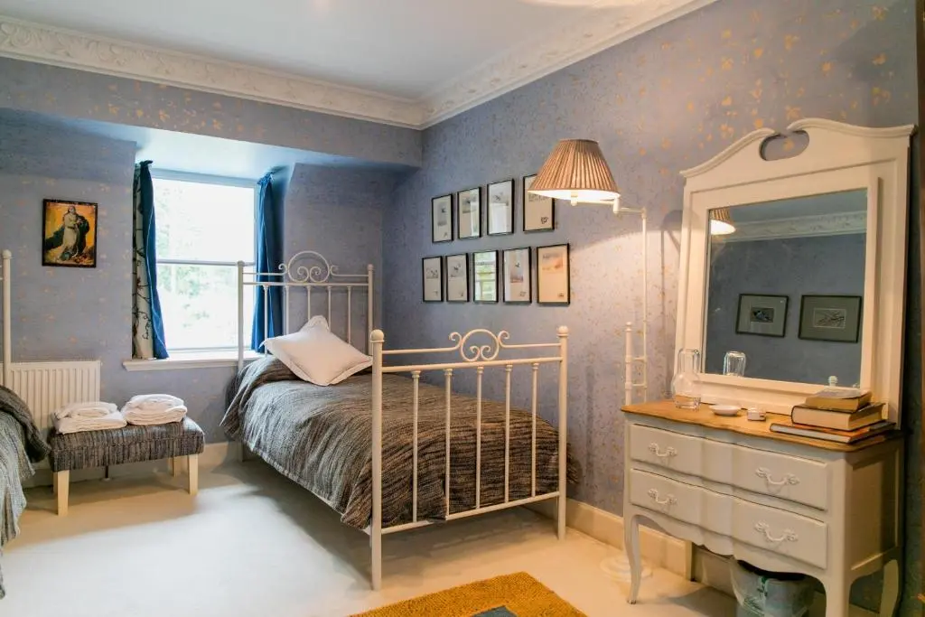 a bedroom with a bed and a dresser and a mirror at Scatwell House in Garve