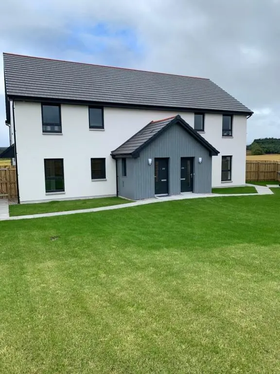 a white house with a large grass yard at 23 C Allan Gardens in Dornoch