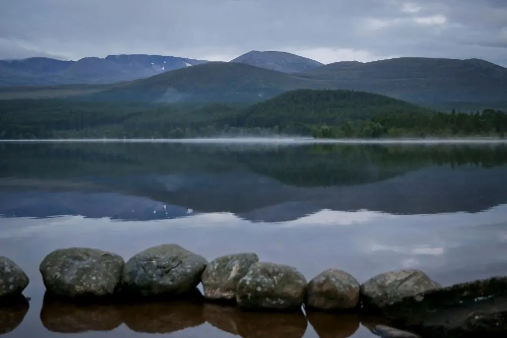a view of a lake with rocks in the water at Cairngorm Lodge Youth Hostel in Loch Morlich