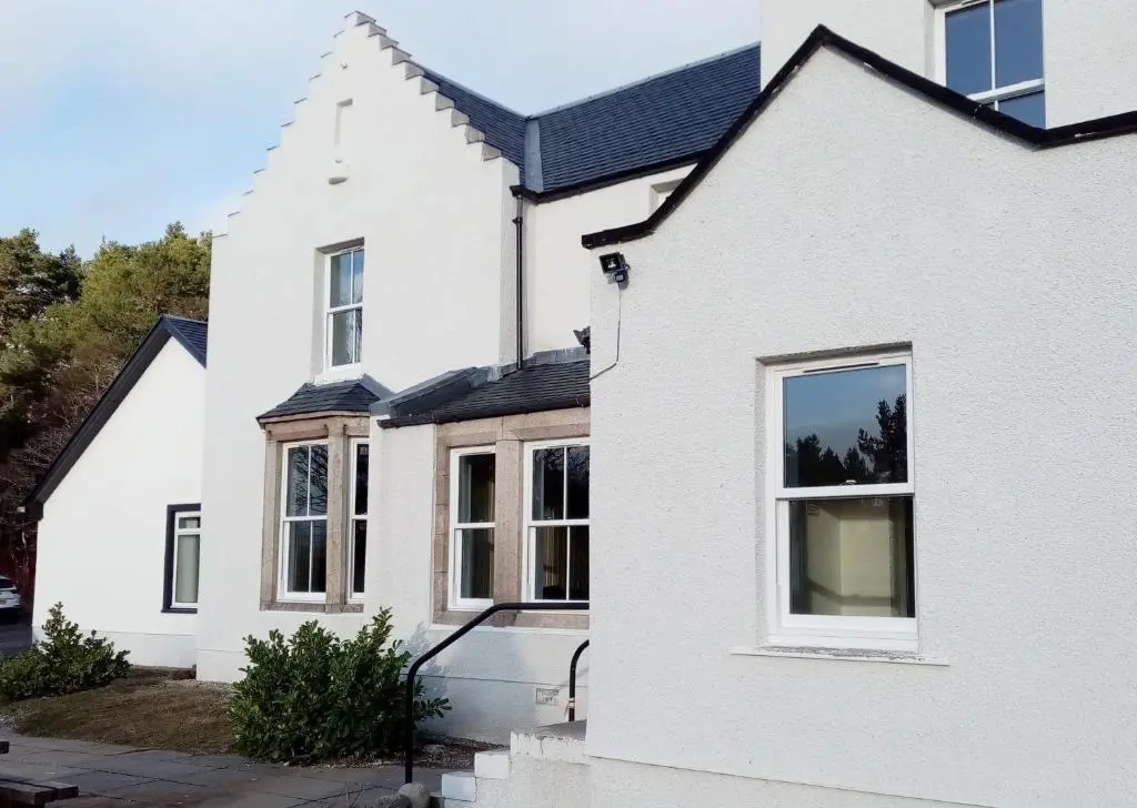 a white house with a black roof at Cairngorm Lodge Youth Hostel in Loch Morlich