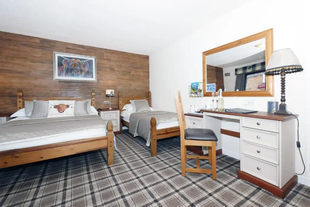 a bedroom with two beds and a desk and a mirror at Ardentorrie Guest House in Inverness