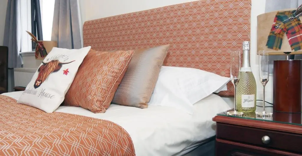 a bed with pillows and a bird on a pillow at Ardentorrie Guest House in Inverness