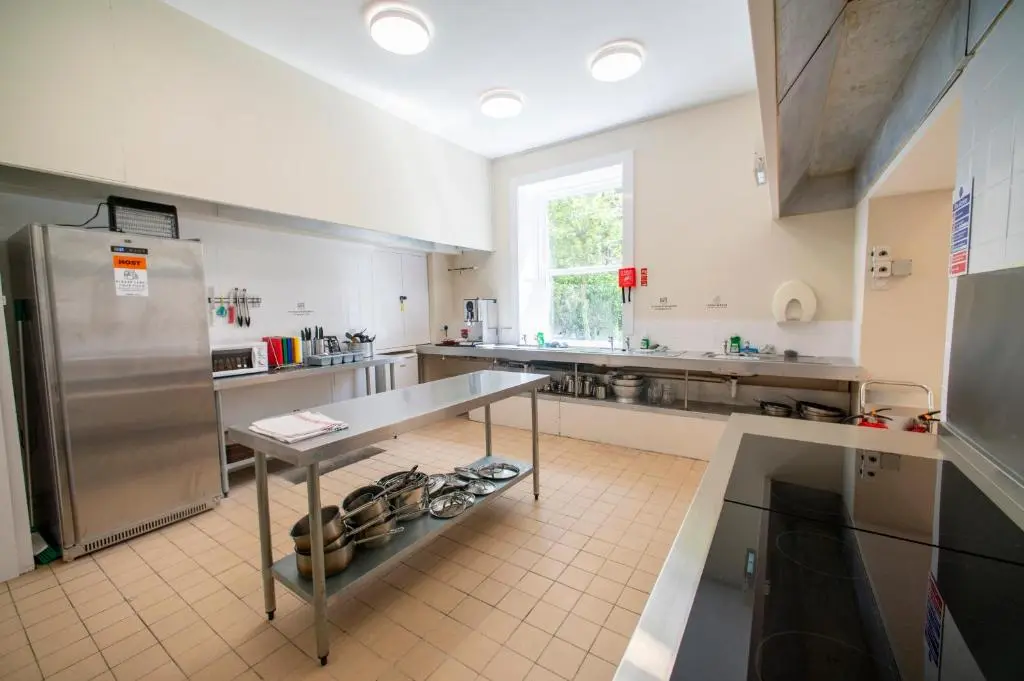 a large kitchen with a table and a stainless steel refrigerator at Braemar Youth Hostel in Braemar
