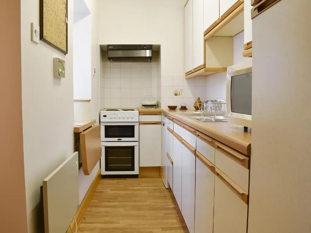a kitchen with white cabinets and a stove top oven at Spey Cottage in Aberlour