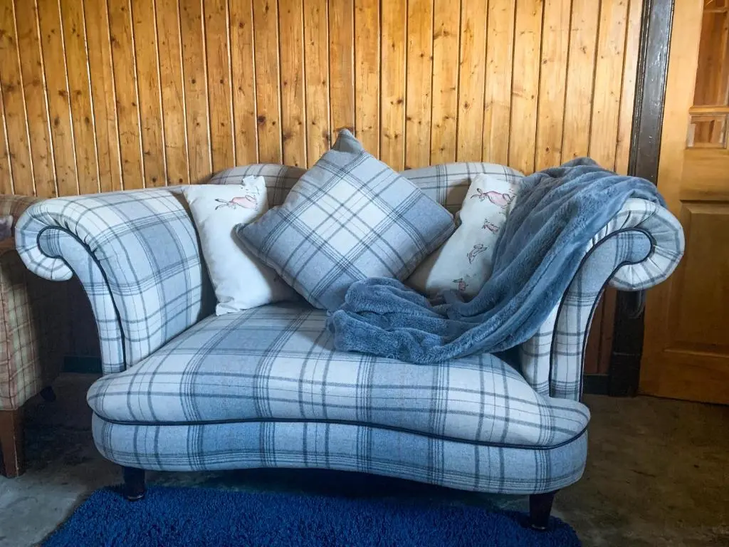a blue plaid chair with a blanket on it at Mains Of Auchmedden Cottage in Pennan