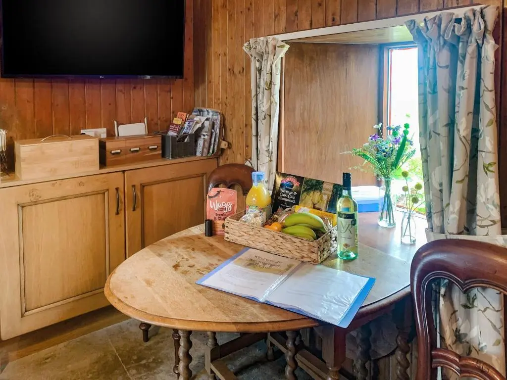 a table with a basket of fruit and a television at Mains Of Auchmedden Cottage in Pennan