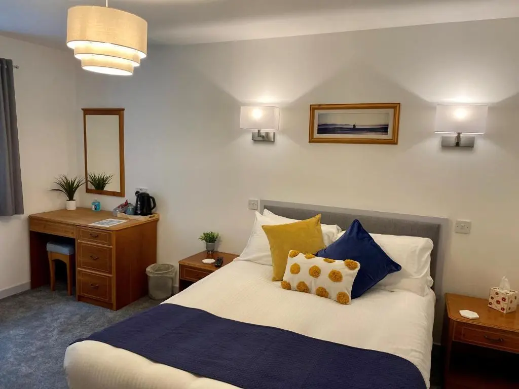 a bedroom with a bed with blue and yellow pillows at The 1645 Inn in Nairn