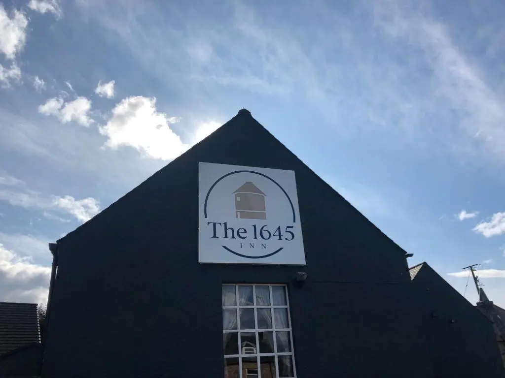 a black building with a sign on the top of it at The 1645 Inn in Nairn