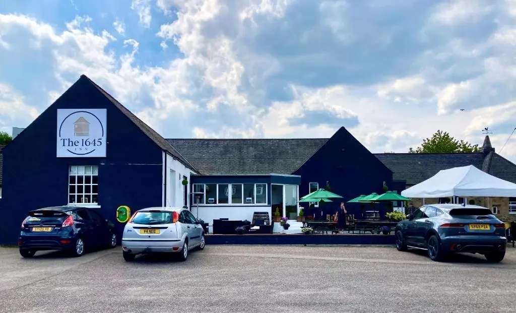 a blue building with cars parked in a parking lot at The 1645 Inn in Nairn