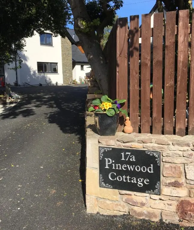 a sign in front of a brick wall with a flower pot at Pinewood Cottage Apartment & B&B Inverness in Inverness