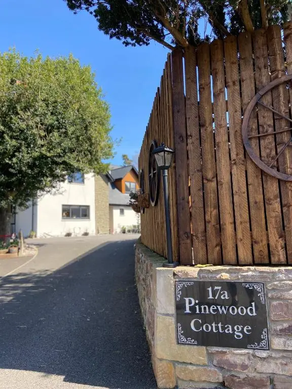 a wooden fence with a sign next to a street at Pinewood Cottage Apartment & B&B Inverness in Inverness