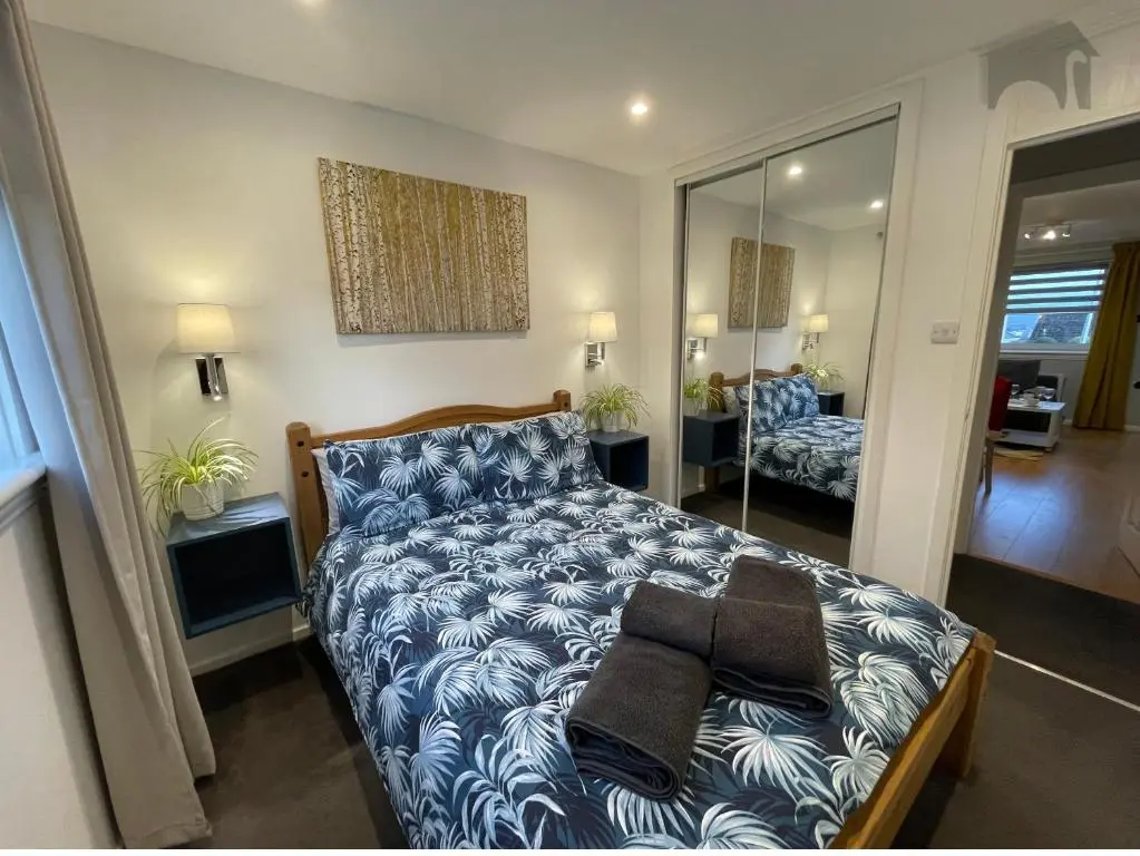 a bedroom with a bed with a blue and white comforter at Highfield apartment in Inverness