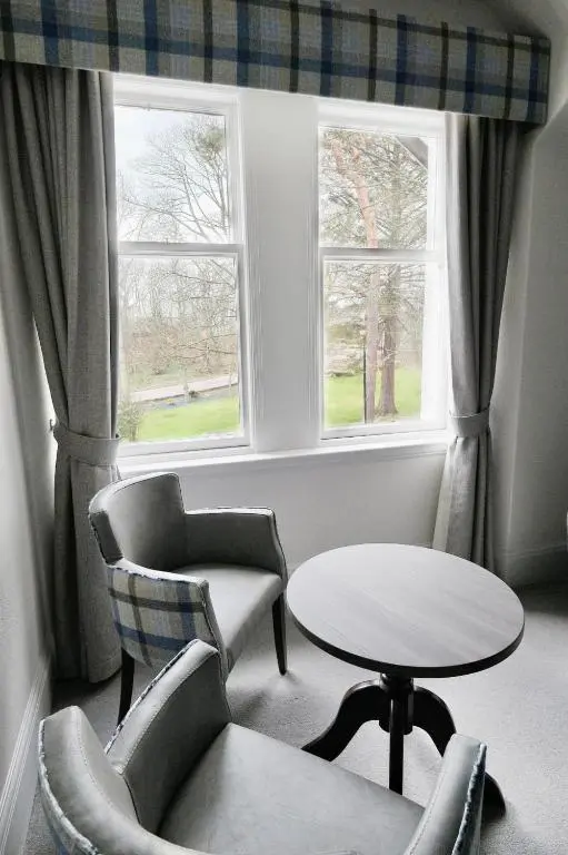 a room with a table and chairs and two windows at Fife Lodge Hotel in Banff